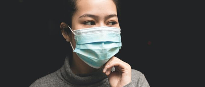 woman wearing teal mask and gray turtle-neck shirt
